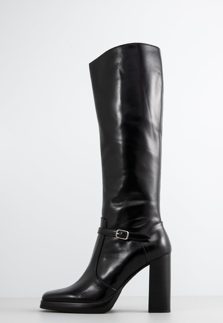 Bottes en cuir noires montantes avec une finition brillante, talon carré solide et une sangle sur le côté avec un petit détail de boucle en argent.