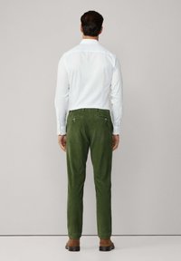 Groene corduroybroek met een slim fit, voorzien van achterzakken en een gladde textuur, gecombineerd met een wit overhemd.