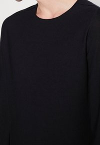 Schwarzer Pullover mit langen Ärmeln und Rundhalsausschnitt, aus weichem Stoff gefertigt. Einfaches Design ohne sichtbare Muster oder Akzente, geeignet zum Schichten.