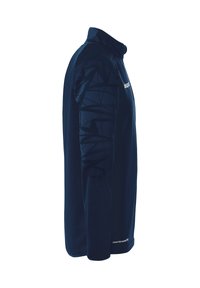 T-shirt de sport à manches longues bleu marine avec un col haut, présentant des motifs géométriques noirs texturés sur l'épaule et un logo subtil à l'avant.