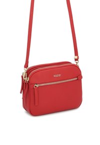Czerwona torba crossbody z dwiema zamkniętymi na zamek komorami, teksturowana powierzchnia, złote akcenty, regulowany pasek. Nazwa marki "kazar" wyświetlona.
