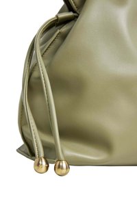 Bolso de cuero verde oliva con una forma estructurada, que cuenta con cuerdas de ajuste y acentos metálicos en tono dorado en los extremos. Textura suave.