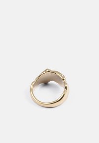 Guldfarvet ring med et bølget, struktureret design. Glatte, afrundede kanter og en hul indre, der viser dristige, organiske former.