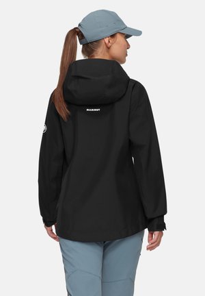 Schwarze wasserdichte Jacke mit Kapuze, mit einem Logo auf der Rückseite und verstellbaren Bündchen, kombiniert mit hellblauen Hosen.