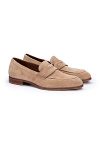 Suede loafers in lichtbeige met een ronde neus en gestikte details, voorzien van een lage gestapelde hak en subtiele accenten op de vamp.