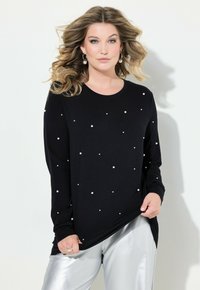 Maglietta nera a maniche lunghe decorata con dettagli bianchi a forma di perle, abbinata a pantaloni argentati lucidi. Tessuto morbido, vestibilità comoda, scollo rotondo.