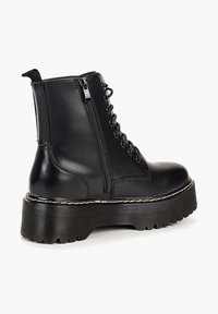 Bottines en cuir noir avec un bout arrondi, un laçage à l'avant, une fermeture éclair sur le côté, une semelle épaisse et une semelle texturée.