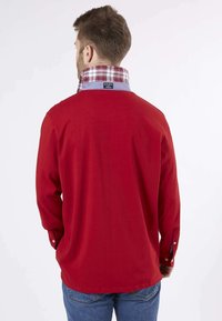 Chemise rouge à manches longues avec un col à carreaux, un corps uni et des poignets boutonnés. Le tissu a l'air lisse avec une coupe décontractée.