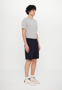 Gray cotton t-shirt and navy elastic waist shorts, paired with light sneakers. The outfit features a simple, casual design.