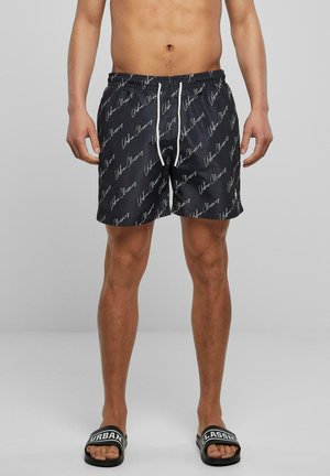 Schwimmshorts aus schwarzem Stoff mit einem weißen handgeschriebenen Logomuster, elastischem Bund mit Kordelzug und einer Länge über dem Knie.