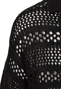 Juodas megztinis su atviru, nėriniuotu raštu, turintis raštuotą apykaklę ir tekstūrinę siūlų struktūrą, suteikiančią lengvą išvaizdą.