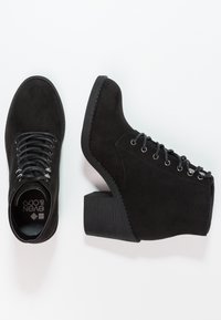 Bottines en daim noir avec bout arrondi, design à lacets, œillets argentés et talon épais texturé.