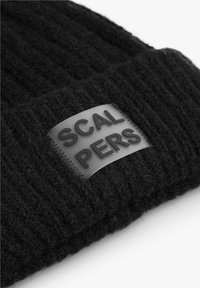 Gorro de lana negro con textura acanalada, que presenta una etiqueta rectangular de goma negra grabada con la palabra "SCALPERS."