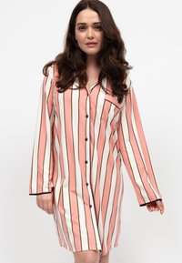 Nightdress a maniche lunghe a righe rosa e bianche con bordo e bottoni neri, dotata di una tasca sul petto sinistro. Tessuto morbido, lunghezza fino al ginocchio.