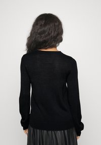 Schwarzer Strickpullover mit langen Ärmeln und Rundhalsausschnitt, von hinten präsentiert, aus einem weichen, strukturierten Stoff.