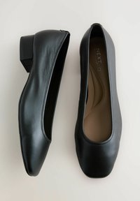 Bailarinas negras de piel suave, con un bajo tacón cuadrado, puntera redondeada y una plantilla acolchada con diseño minimalista.