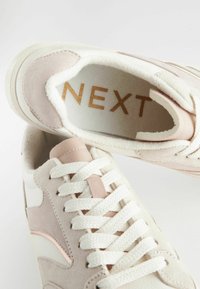 Sneakers in camoscio rosa chiaro e sintetico crema, con lacci bianchi, dotati di una morbida fodera interna e del logo dorato "NEXT" sulla soletta.