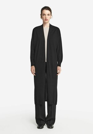 Sort lang cardigan lavet af et let, tekstureret stof med åben front og drop skuldre, parret med sorte bukser med bred ben.