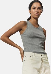 Top de tirantes gris con texturizado, diseño entallado y acabado suave, combinado con pantalones de tiro alto color blanco roto con detalles de botones.