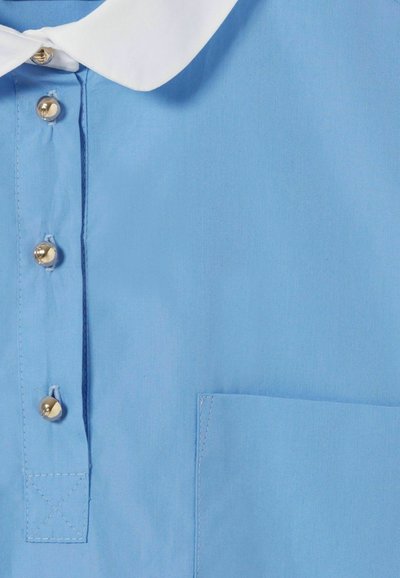 Camisa azul clara con cuello blanco, con botones dorados y un bolsillo en el pecho. Tejido suave con detalles de costura limpios.