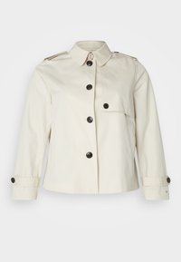 Kremowa krótka kurtka ze stójką, zapinana na guziki, z dwoma bocznymi kieszeniami oraz czarnymi guzikami dla kontrastu.