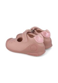 Zapatillas de goma rosas con correas de Velcro, puntera redonda, pequeños cortes en los laterales y un acento brillante en el talón. Logo de Biomechanics visible.