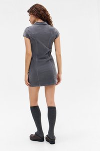 Siva haljina do kralih s kratkim rukavima, s ovratnikom, prilježno oblikovana i s vidljivim detaljima šivanja. Uparen s visokom rebrastom čarapama do koljena.