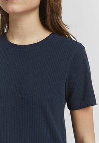 Marineblå tekstureret kortærmet skjorte med rund halsudskæring. Stoffet har et subtilt ribbet mønster.