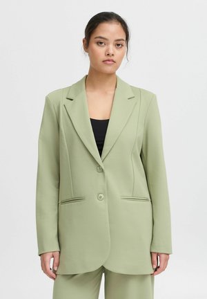 Světle zelený blazer s tailored designem, jednoradovým zapínáním na knoflíky, dvěma předními kapsami a decentními švy.