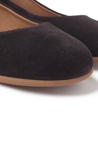 Bailarinas de ante negro con punta redondeada y una textura suave. Cuentan con una suela de goma color beige, ofreciendo un diseño minimalista y elegante.
