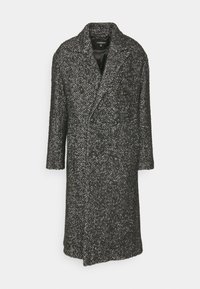 Černobílý vlněný kabát se vzorem rybí kostí, s dvouřadým zapínáním, velkými klopami a dlouhými rukávy. Má dvě knoflíkové ozdoby.