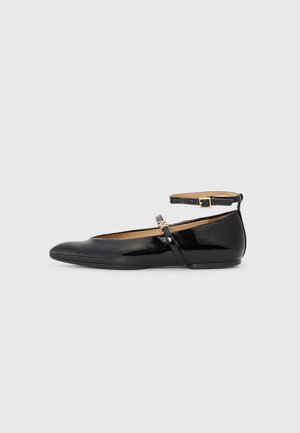 Black patent leather ballet flats with a rounded toe, ankle strap, and small buckle detail. Smooth texture and minimalistic design.