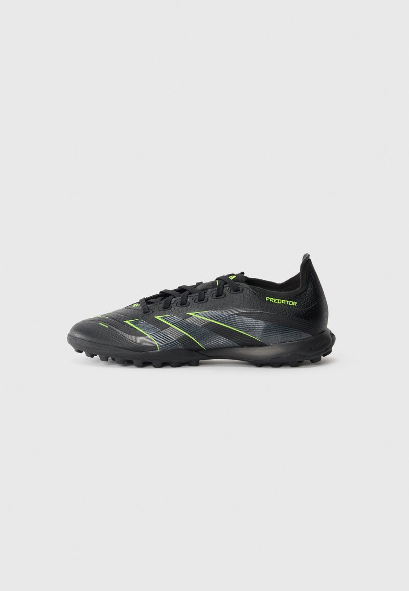 Chaussure de football noire et grise avec des accents vert fluo, des lacets et une semelle texturée conçue pour une utilisation sur gazon ou sol ferme.