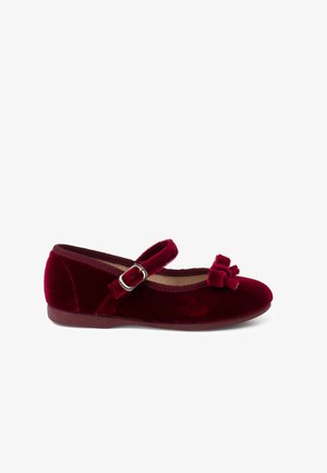 Burgundy samettikengät pyöreällä kärjellä, hopeanaulakkeella varustetulla hihnalla ja koristeellisia kuvioita edessä. Pehmeä pinta ja matala profiili.