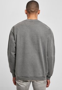 Felpa grigia con collezione a girocollo, spalle scese e polsini a costine. Presenta una texture morbida e una vestibilità rilassata. Vista posteriore semplice.