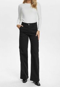 Pantalon noir à jambes larges en mélange de coton, avec taille haute, fermeture à bouton métallique et poches latérales. Texture lisse, coupe structurée.