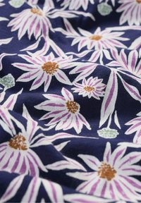 Navy fabric with a floral pattern featuring large pink and white flowers, green leaves, and brown centers; soft texture with natural draping.