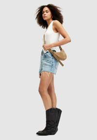 Denimshorts med fransat avslut, vit ribbad tanktop och en tan mocka crossbody-väska. Svarta lädercowboyboots med intrikata sömmar.