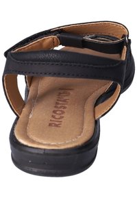 Černé kožené sandály s otevřenou patou, nastavitelným páskem, béžovou podšívkou a plochou podešví. Logo vytištěné na vložce. Minimalistický design.