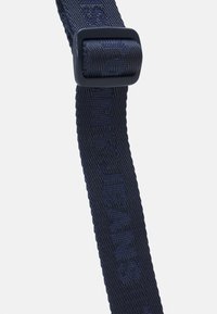 Cinturino intrecciato blu navy con finitura strutturata, dettagli del marchio in rilievo e fibbia rettangolare per la regolazione.