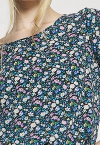 Tissu à motif floral avec de petites fleurs blanches, roses et bleues sur un fond noir ; léger, avec une coupe ample et un design hors épaule.