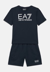 Tumesinised puuvillased lühikesed püksid ja T-särgi komplekt, millel on ees valge EA7 Emporio Armani logo; lihtne disain, vabaaja lõikega.