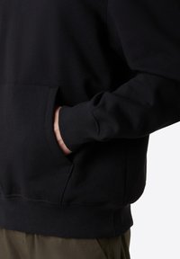 Černá mikina se přední kapsou, žebrovanými manžetami a spodním lemem. Vyrobena z měkké látky s hladkým povrchem.