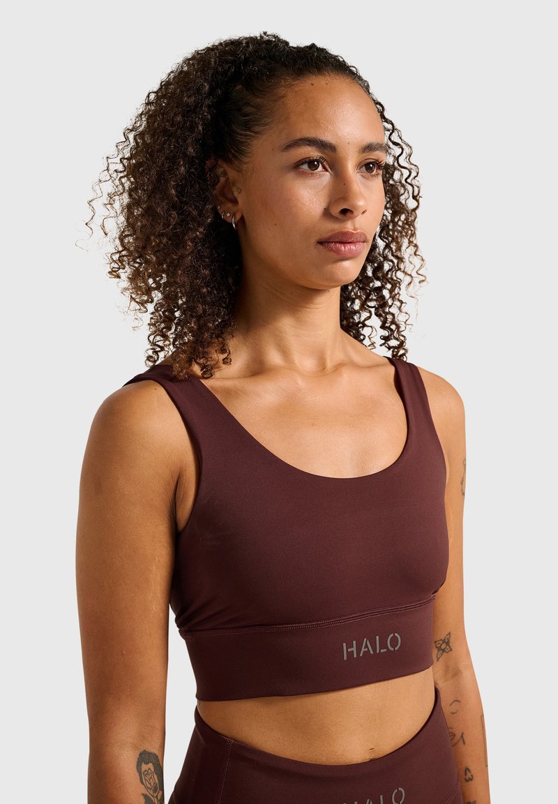 Brun sports-bh lavet af glat, elastisk stof. Har en bred kant med "HALO"-logo, rund halsudskæring og brede stropper.