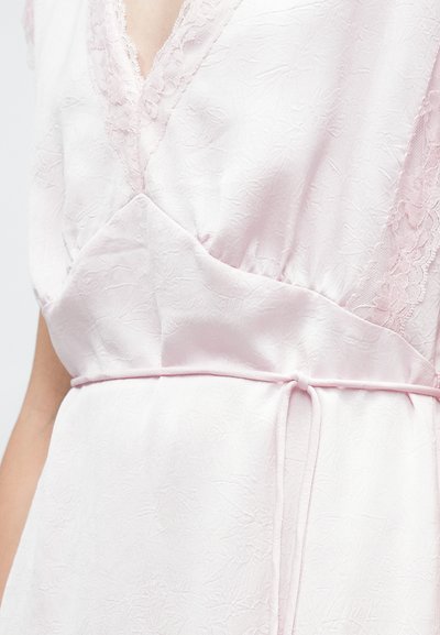 Ροζ απαλό φόρεμα από ύφασμα με δαντέλα στους ώμους και λεπτή ζώνη δεμένη γύρω από τη μέση, που δείχνει το πάνω μέρος του κορμού και το χέρι.