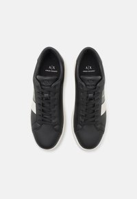 Sneaker in pelle nera con accenti bianchi e grigi, punta tonda, design con lacci, suola in gomma e soletta con marchio.