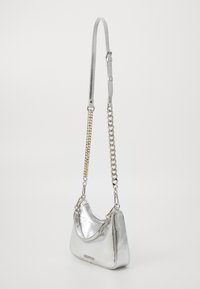 Metalen zilveren handtas met een gebogen vorm, voorzien van een schouderband met een mix van zilveren ketting en een vlak leren gedeelte.