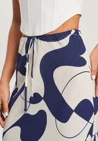Gonna leggera in crema con un audace motivo astratto blu navy, cintura elastica con cordoncino e texture liscia e fluida.