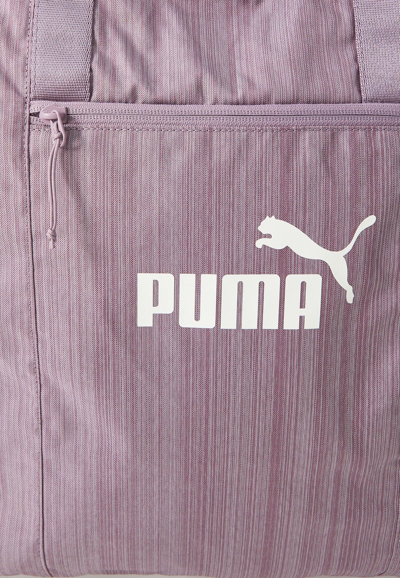 Borsa a tracolla a strisce viola realizzata in tessuto testurizzato. Presenta una tasca frontale con zip e un grande logo PUMA bianco. Design semplice e funzionale.