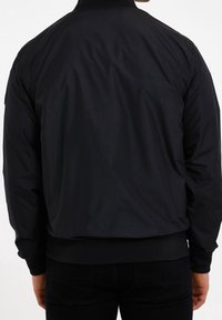 Chaqueta bomber negra, tejido suave, puños y dobladillo acanalados, diseño ligero, corte recto, sin logos ni patrones visibles.